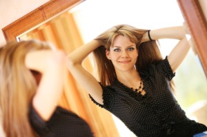 Beautiful young woman looking in the mirror